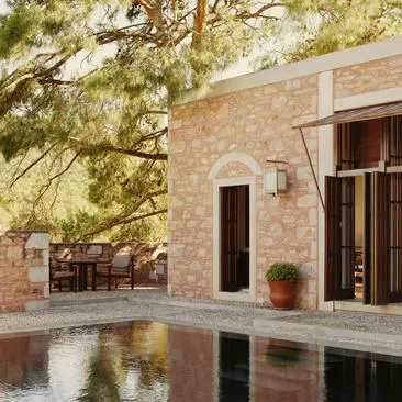 Exterior of a stone pavilion at Amanruya with a reflecting pool and pine trees.