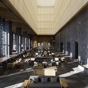 Amanemu resort lobby with soaring ceilings, featuring seating areas and floor-to-ceiling windows overlooking the landscape.