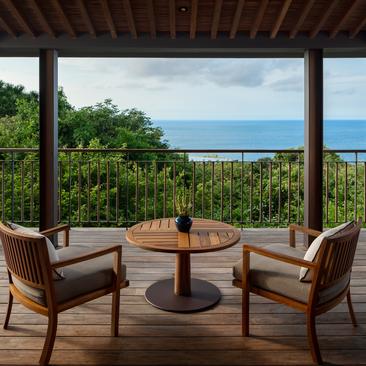 Wooden terrace at Amanoi with two chairs facing the sea, framed by open doors and tropical greenery.