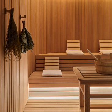 Wooden banya interior at Aman New York with tiered seating, towels, and cedar paneling.