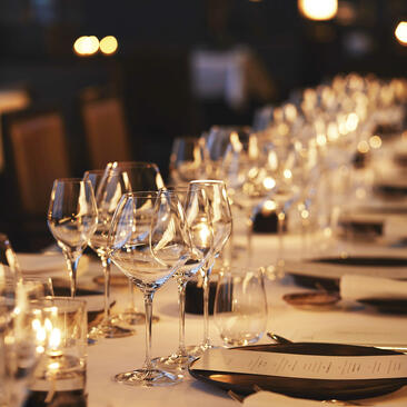 Candlelit gala dinner table setting at Aman Tokyo hotel, with rows of empty glasses and place settings.
