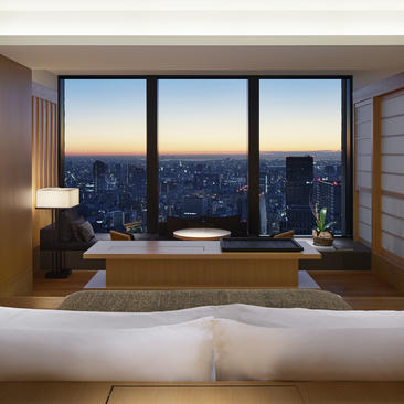 Premier Room at Aman Tokyo with floor-to-ceiling windows overlooking the city at dusk.