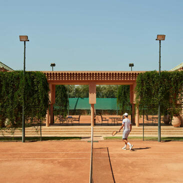 Tennis court at Amanjena resort in Marrakech, Morocco, with red clay surface and traditional architecture backdrop.