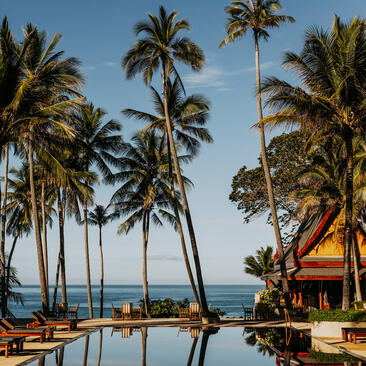 Main pool at Amanpuri surrounded by palm trees and reflecting still water, Thailand.