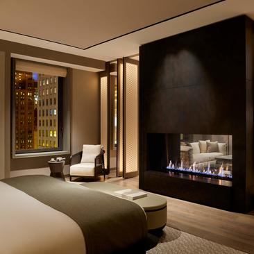 Suite con camino e poltrona presso Aman New York hotel.