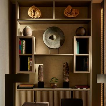 Estante em madeira com prateleiras exibindo objetos decorativos e livros, na suíte do hotel Aman New York.