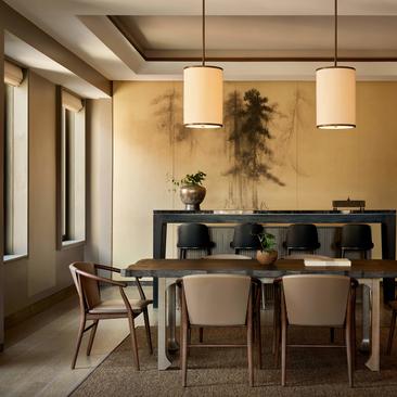 Sala de jantar da suíte Aman com mesa de madeira, cadeiras modernas e luz natural do Aman New York.