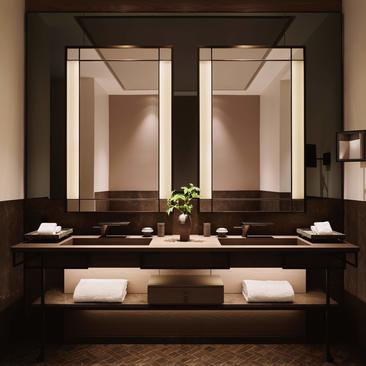 Banheiro da suíte de canto com dupla espelho iluminado, pias em mármore e detalhes minimalistas no Aman New York.