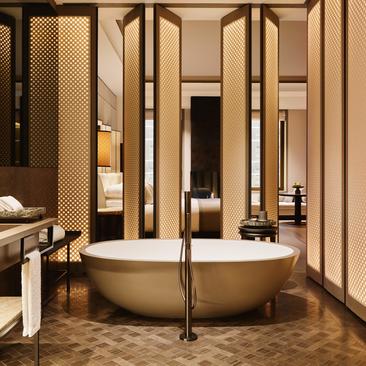 Fifth Avenue Junior Suite bathroom at Aman New York, featuring a freestanding bronze soaking tub and brass fixtures.
