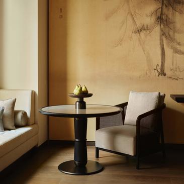 Serene seating area at Aman New York with round pedestal table, sculptural chair, and minimalist wall art.
