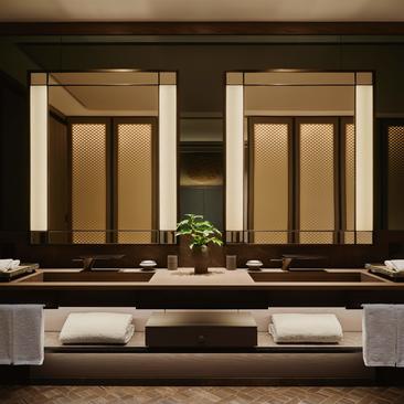 Aman New York's Fifth Avenue Suite features two wooden doors with a potted plant on the marble counter between them.