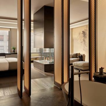 Entrada da Grand Suite com portas de madeira, closet integrado e vista para o quarto principal no Aman New York.