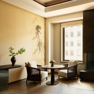 Sunlit principal bedroom seating area at Aman New York with floor-to-ceiling windows overlooking the city.