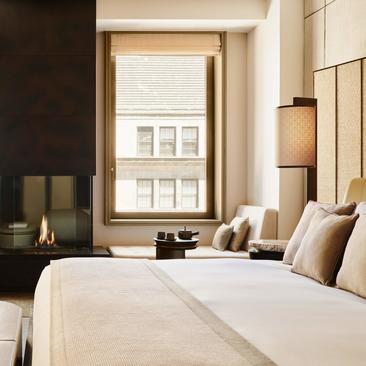 Premier Sanctuary Suite at Aman New York with dual beds, floor-to-ceiling window, and neutral furnishings.