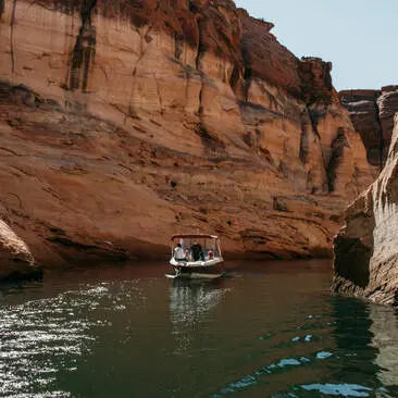 Barca a motore naviga lungo il canyon rosso di arenaria con acque turchesi ad Amangiri.
