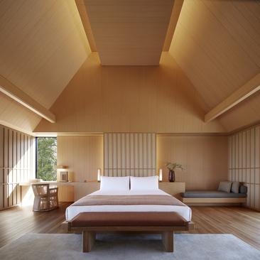 Principal bedroom in a suite or villa at Amanemu, Japan, with wooden bed frame and warm ambient lighting.