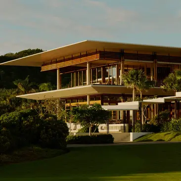 Casa Grande exterior at Amanera resort, Dominican Republic, with wooden architecture and manicured gardens at dusk.