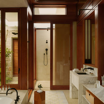 Salle de bains à Amanera resort, avec boiseries en teintes chaudes, double vasque et douche vitrée.