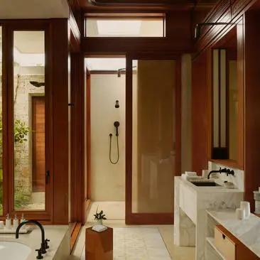 Cuarto de baño de Amanera con mueble de madera, espejo grande y detalles de piedra natural.