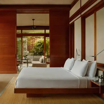 Amanera resort principal bedroom with terracotta walls, wooden platform bed, and garden views through open doors.