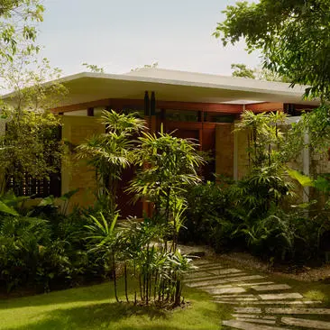 Exterior view of an accommodation pavilion at Amanera resort, surrounded by lush tropical greenery and a manicured lawn.
