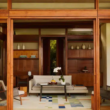 Spacious living room at Amanera resort with warm wood panelling, open shelving, and contemporary furnishings.