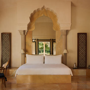 Principal bedroom with ornate arched headwall and pool pavilion views at Amanbagh.