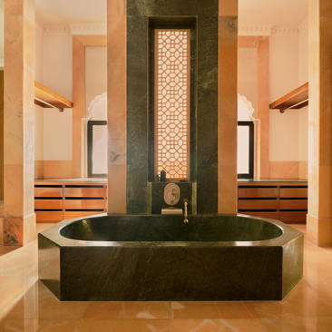 Bathroom at Amanbagh with sunken black stone bathtub and warm stone walls.