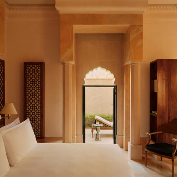 Courtyard Haveli Suite bedroom at Amanbagh with arched doorway and warm terracotta walls.