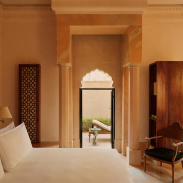 Principal bedroom in Courtyard Haveli Suite at Amanbagh, with arched doorway and warm terracotta tones.