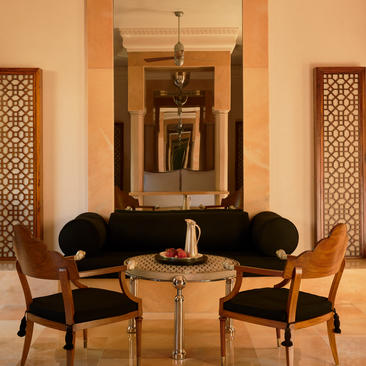 Sitting area in a Courtyard Haveli Suite at Amanbagh, with two black chairs flanking a round table beneath a mirror.