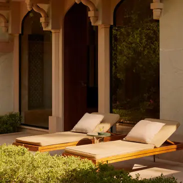 Garden Haveli Suite with cushioned seating area overlooking landscaped grounds at Amanbagh, India.