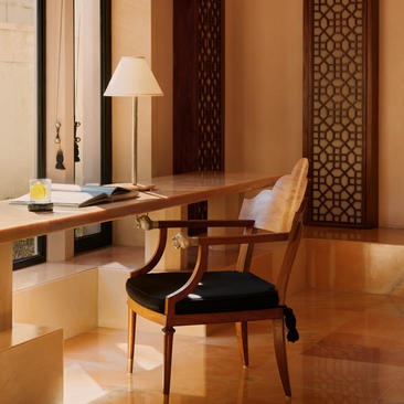Workspace at Amanbagh with wooden desk, chair and table lamp beneath carved wooden screens.