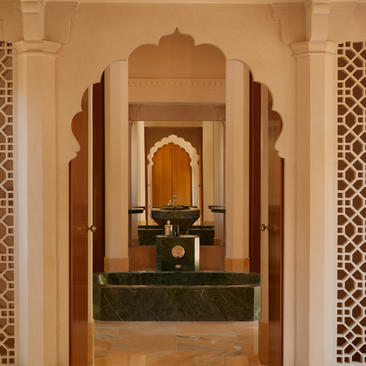 Arched bathroom doorway at Amanbagh with traditional architectural detailing and marble basin.