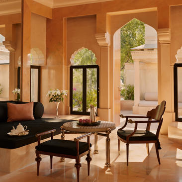 Terrace Haveli Suite living area at Amanbagh with warm stone walls, arched windows, and traditional seating.