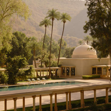 Terrace view of Haveli Suite pool at Amanbagh, with palm trees and desert hills beyond.