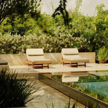 Deux chaises longues blanches face à une piscine aux eaux calmes à Amanera, resort en République dominicaine.