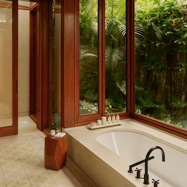 Salle de bains d'une casita avec baignoire et portes coulissantes ouvrant sur la verdure, Amanera, République Dominicaine.