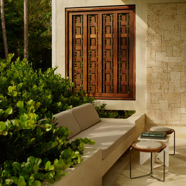 Casita exterior at Amanera resort with wooden door, stone walls, and seating area surrounded by greenery.