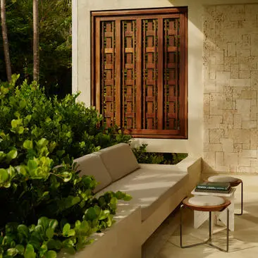 Casita exterior at Amanera resort with wooden door, stone walls, and lush greenery at dusk.