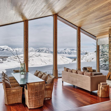 Amangani home interior with floor-to-ceiling windows overlooking snow-capped mountains and valley below.