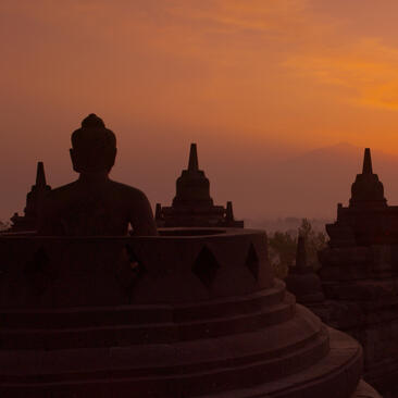 Borobudur temple silhouetted against an orange dawn sky in Indonesia, near Amansara.