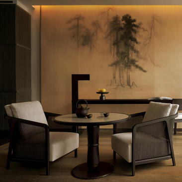 Lounge area in a Premier Suite at Aman New York, featuring a dining table with black chairs and minimalist Asian-inspired wall art.
