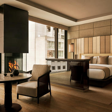 Principal bedroom at Aman New York with fireplace, wooden paneling, and modern furnishings.