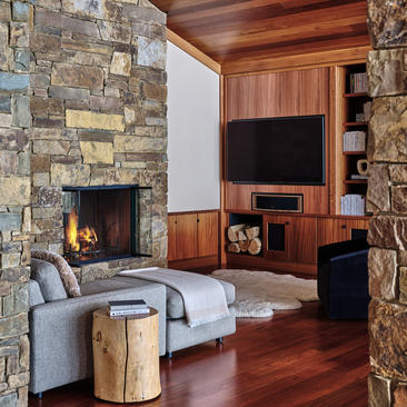 Wapiti home at Amangani featuring stone fireplace, wooden-beamed ceiling, and seating area with hardwood flooring.