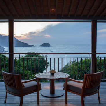 Terrace seating at Amanoi with two chairs facing the ocean at dusk, overlooking coastal waters and distant islands.