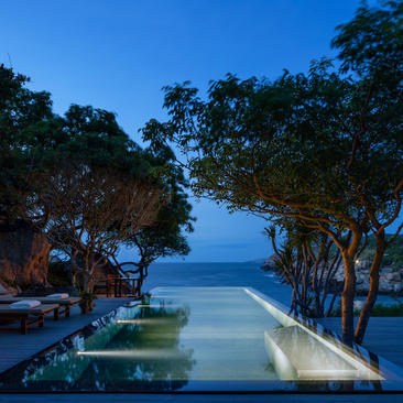 Ocean pool at Amanoi with views towards the sea at dusk, framed by tree-lined pathways.