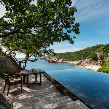 Wooden deck with seating overlooking a secluded cove and turquoise waters at Amanoi, Vietnam.
