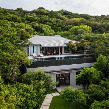 Modern villa with ocean pool at Amanoi, Vietnam, surrounded by lush green landscape and coastal vegetation.