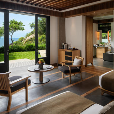 Junior bedroom at Amanoi with ocean views, wooden furnishings, and access to tropical garden terrace.